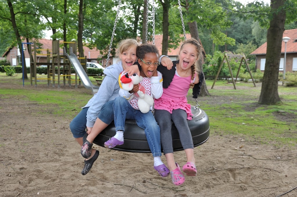 Drie kinderen op een ronde bandenschommel