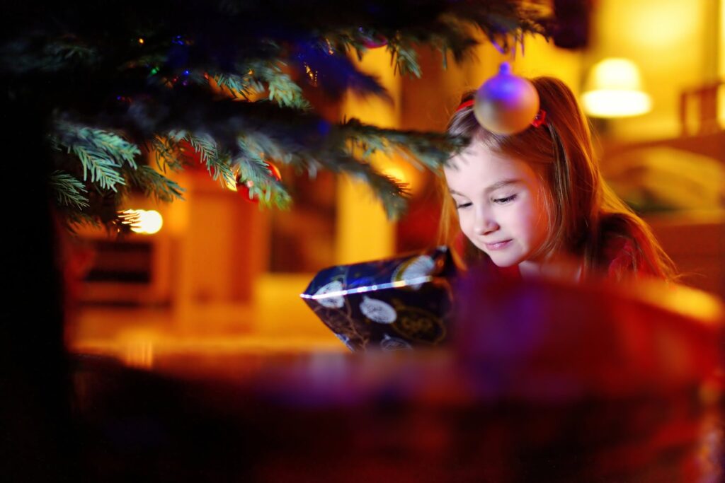 Kerstcadeau voor meisje bij de kerstboom