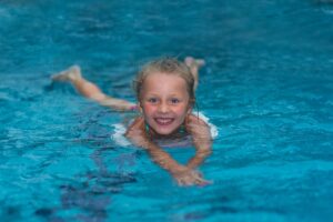 kind zwemt glimlachend naar de camera